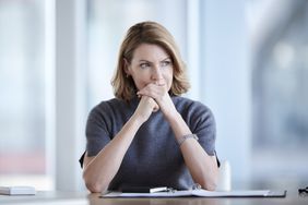 woman thinking at table with binder