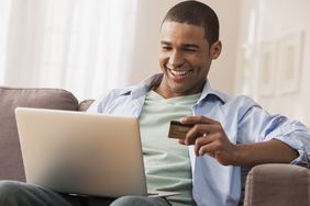 一个男人用他的信用卡网上他的笔记本电脑