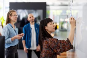 A person writes on a whiteboard.