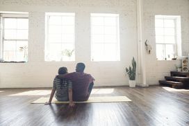 年轻夫妇坐在地毯上阁楼”width=