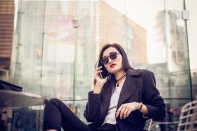 美丽的中国女商人，在大城市享受远离办公室的时光，坐在咖啡馆里，用手机聊天