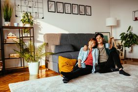 年轻夫妇坐在公寓地板上靠沙发