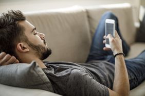 一个人躺在沙发上用智能手机