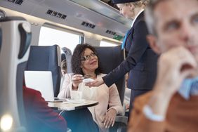 一名女子用信用卡进行非接触式支付，在客运列车上给乘务员付款。
