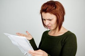 Woman looking at a credit card statement with expression of disbelief