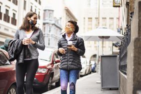 两个女人走在城里的大街上喝咖啡