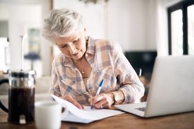 女人做笔记在纸上工作时笔记本电脑