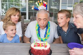 老人和家人一起吹灭生日蛋糕上的蜡烛