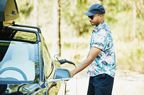 一个戴着墨镜，穿着鲜艳夏威夷衬衫的男人正在给他的电动车充电