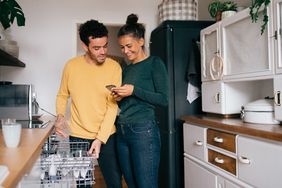 一对夫妇站在厨房里用手机查看他们的抵押贷款余额