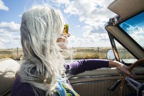 Platinum-haired女人开车可转换在一个阳光明媚的一天