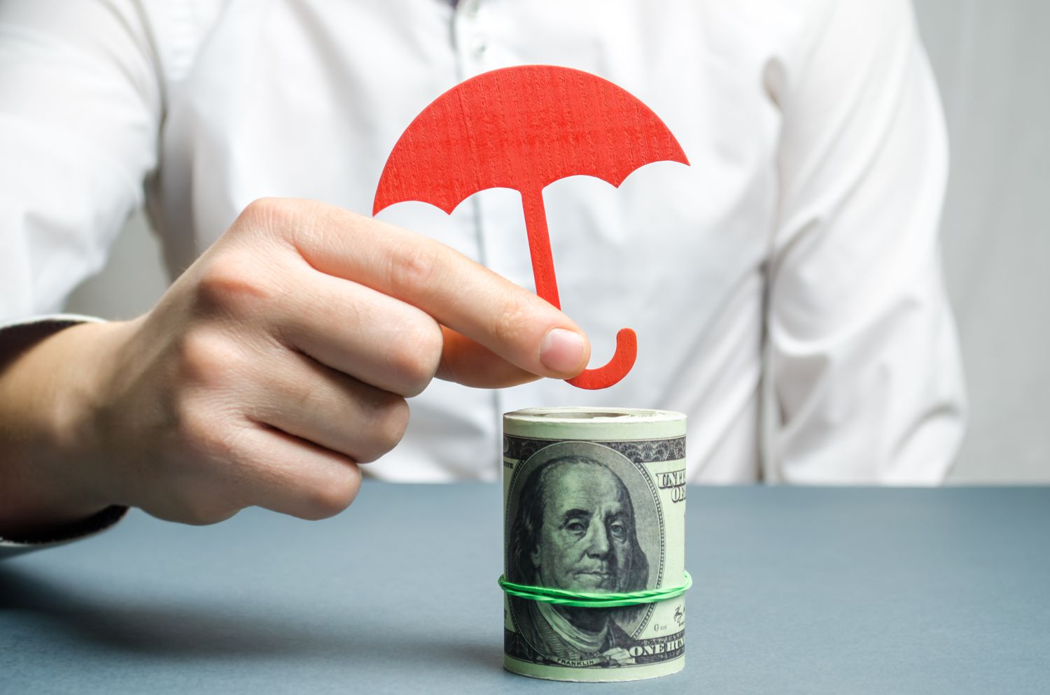 雨伞放在一卷钞票上，以保护它免受风险投资的影响＂class=