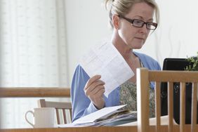 一个拿着账单在笔记本电脑前工作的女人