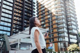 女人拿着手机看高层建筑