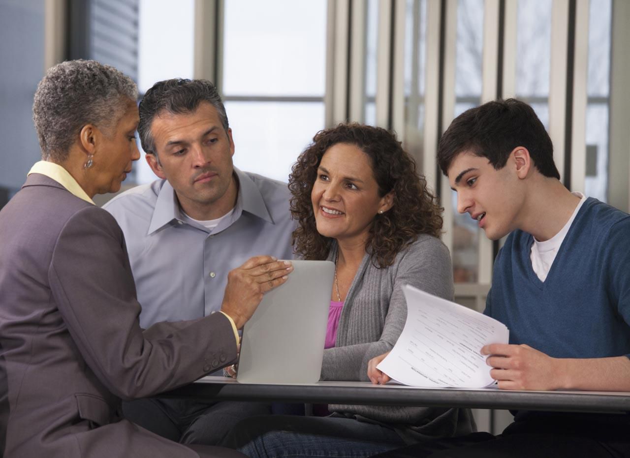 父母和儿子与财务顾问谈论大学费用借款。”class=