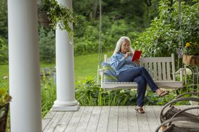 A person on a porch swing reads a book.