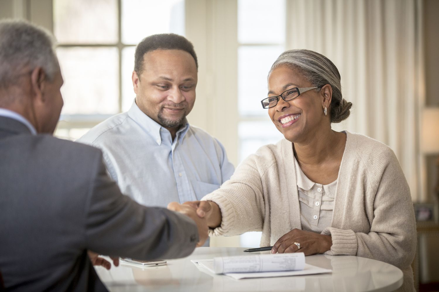微笑的黑人夫妇审查文件与抵押贷款经纪人。