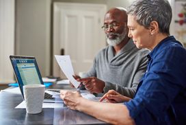 一对夫妇在家里的笔记本电脑前查看他们个人退休账户的余额