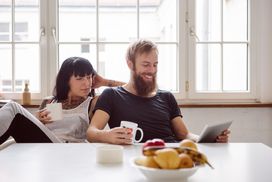 一对夫妇边喝咖啡边看平板电脑。＂width=