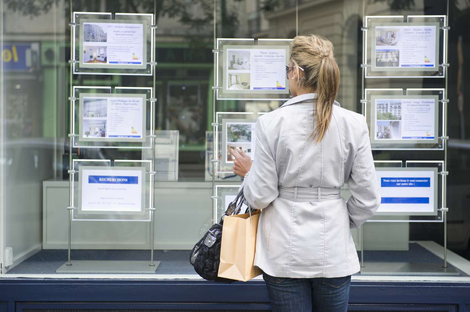 一名女子正在看房地产橱窗里的待售房屋广告