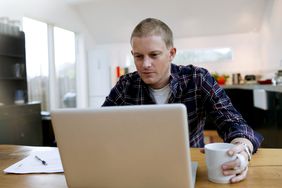 man on computer at home in kitchen