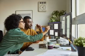 Two people look at a computer screen.