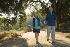 微笑的退休夫妇在银行有足够的存款，在阳光明媚的公园散步