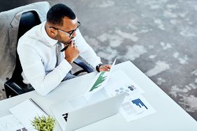 Cropped shot of a handsome young businessman sitting in his office and looking contemplative while reading paperwork