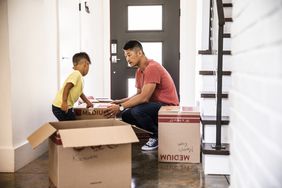 一个男人和一个小男孩搬箱子塞进一个空的回家。”>
          </noscript>
         </div>
        </div>
       </div>
       <div class=
