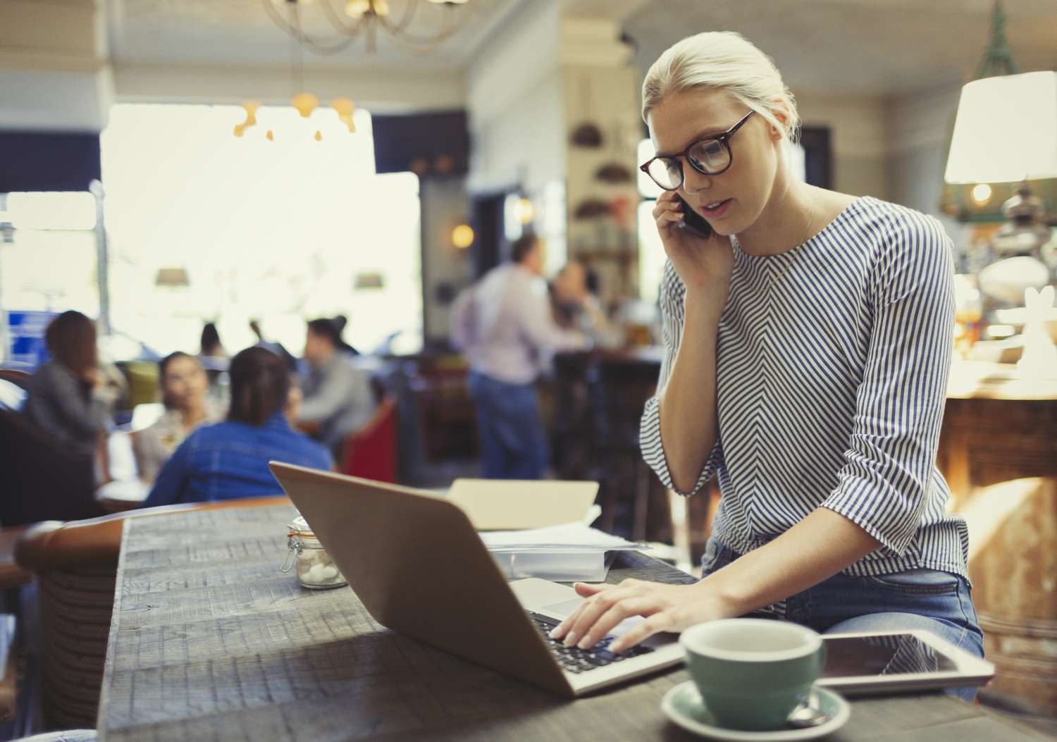 有创意的女商人在咖啡馆打电话和使用笔记本电脑