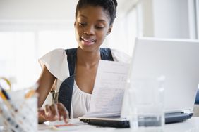 女人坐在笔记本电脑前使用计算器和查看文件