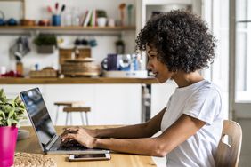 Woman using laptop at table at home