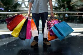 一名男子在购物中心疯狂购物后，手里拿着许多购物袋