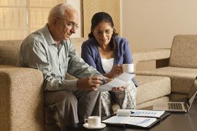 Older couple working in living room, with laptop on coffee table