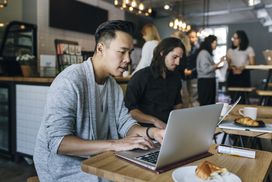 一个人在咖啡馆在笔记本电脑上工作。”width=