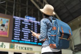 徒步旅行的年轻女子旅游看了看头顶的董事会在机场航班信息终端。