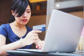年轻的日本女子用她的信用卡在网上购物＂width=