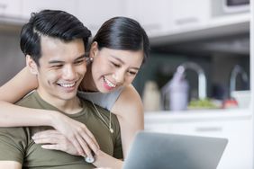 一对年轻夫妇微笑着看着电脑屏幕