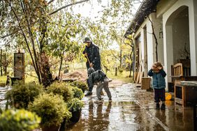 父母和孩子在暴风雨后扫水从前院
