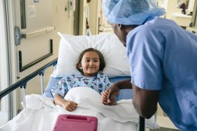 Child in hospital holding medical professional's hand