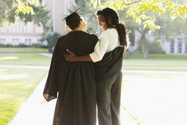 穿着毕业礼服的母女在校园里拥抱在一起