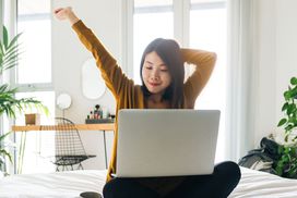女人在使用笔记本电脑盘腿坐在伸展”width=