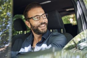 一个带着眼镜微笑的男人坐在驾驶座上
