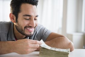 一名男子笑着看着桌上一大堆钞票