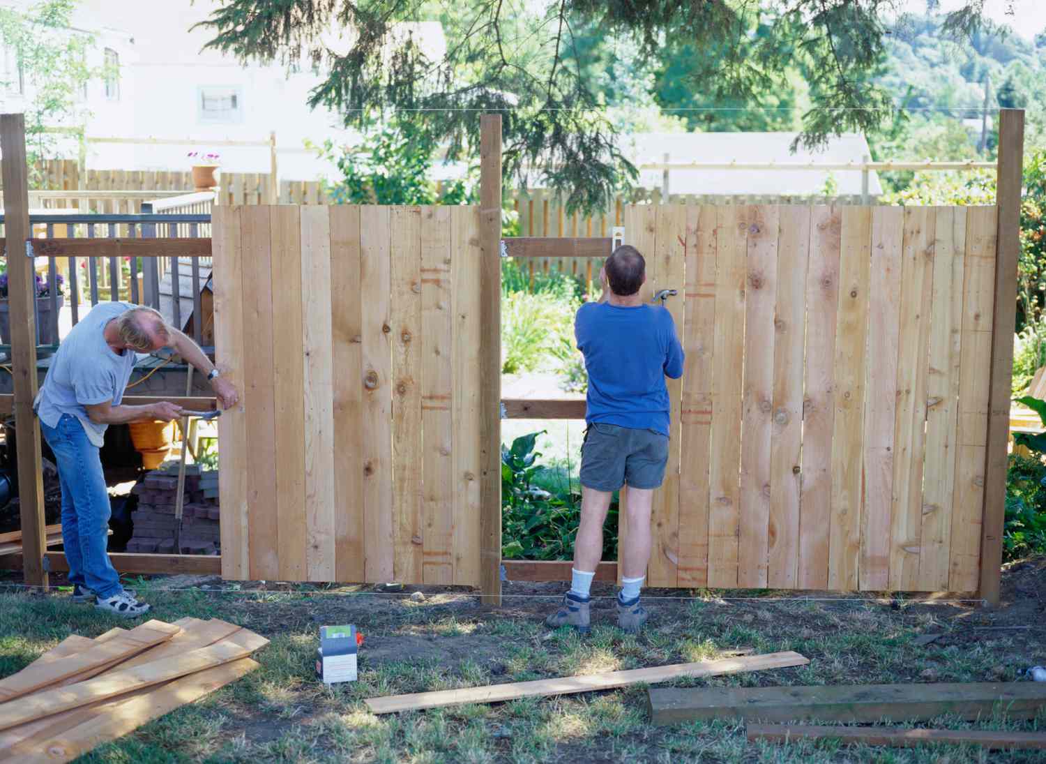 两个木匠在住宅之间建造木栅栏