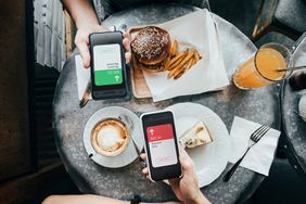朋友们一起在餐厅用餐时，通过智能手机上的数字钱包设备发送/接收餐费的俯视图