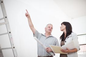一名男子站在金属梯子旁，指着他和一位潜在买家谈论房屋评估。＂>
          </noscript>
         </div>
        </div>
       </div>
       <div class=