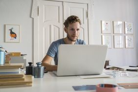 Young man sitting at desk looking at laptop