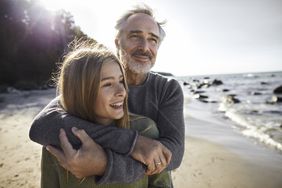 阳光明媚的一天，父亲在海滩上拥抱成年的女儿