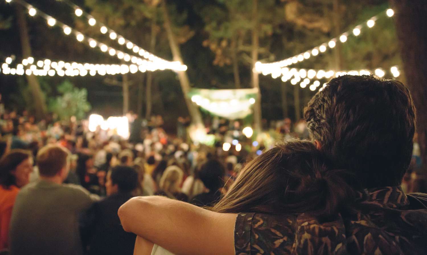 年轻情侣在夜晚的音乐节上拥抱